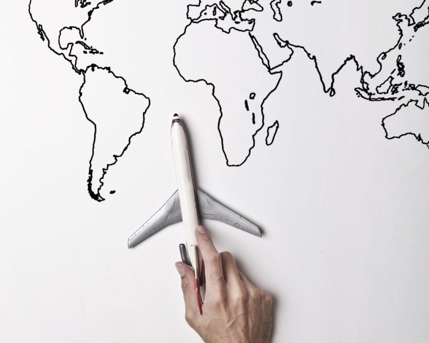 Canva - Person holding small toy airplane against black and white map as concept of travel and vacation
